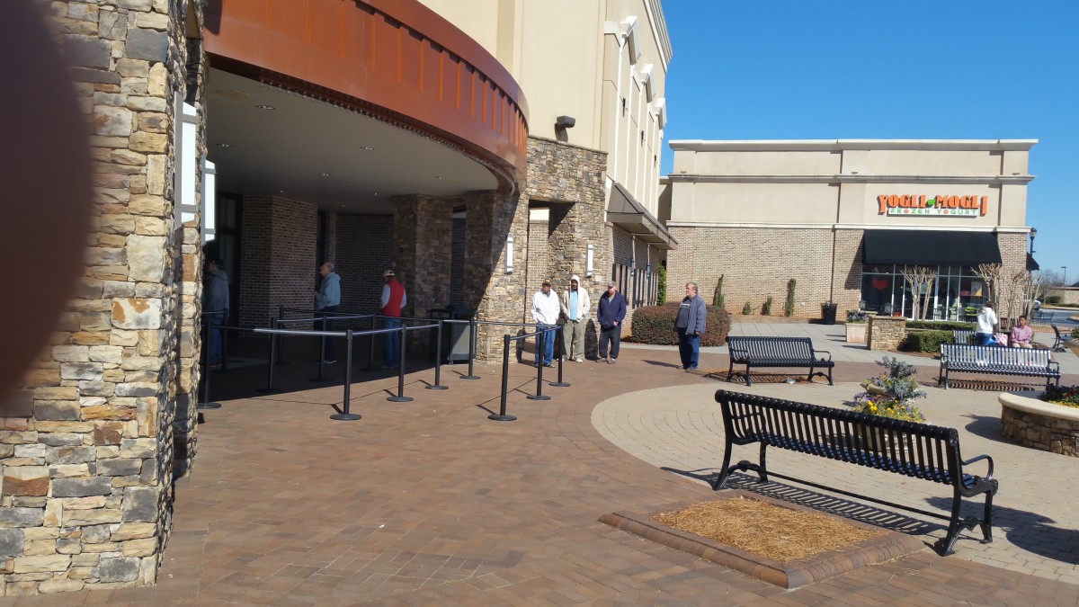 People standing in a line outside a building, maintaining social distancing.