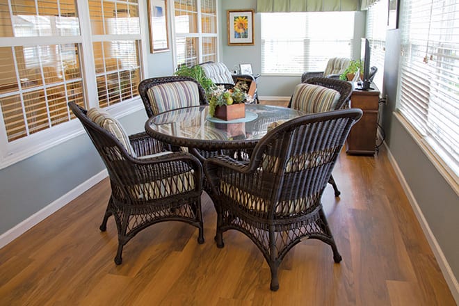 A cozy dining area featuring a round table with rattan chairs in a sunlit room.