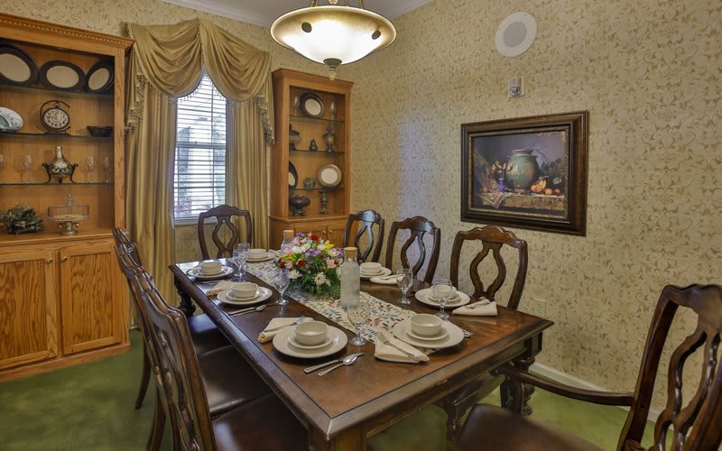 A traditional dining room setup with an elegant table and chairs, complete with place settings and decorative elements.