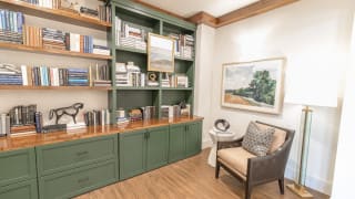 A cozy reading nook with a green bookshelf and comfortable armchair.