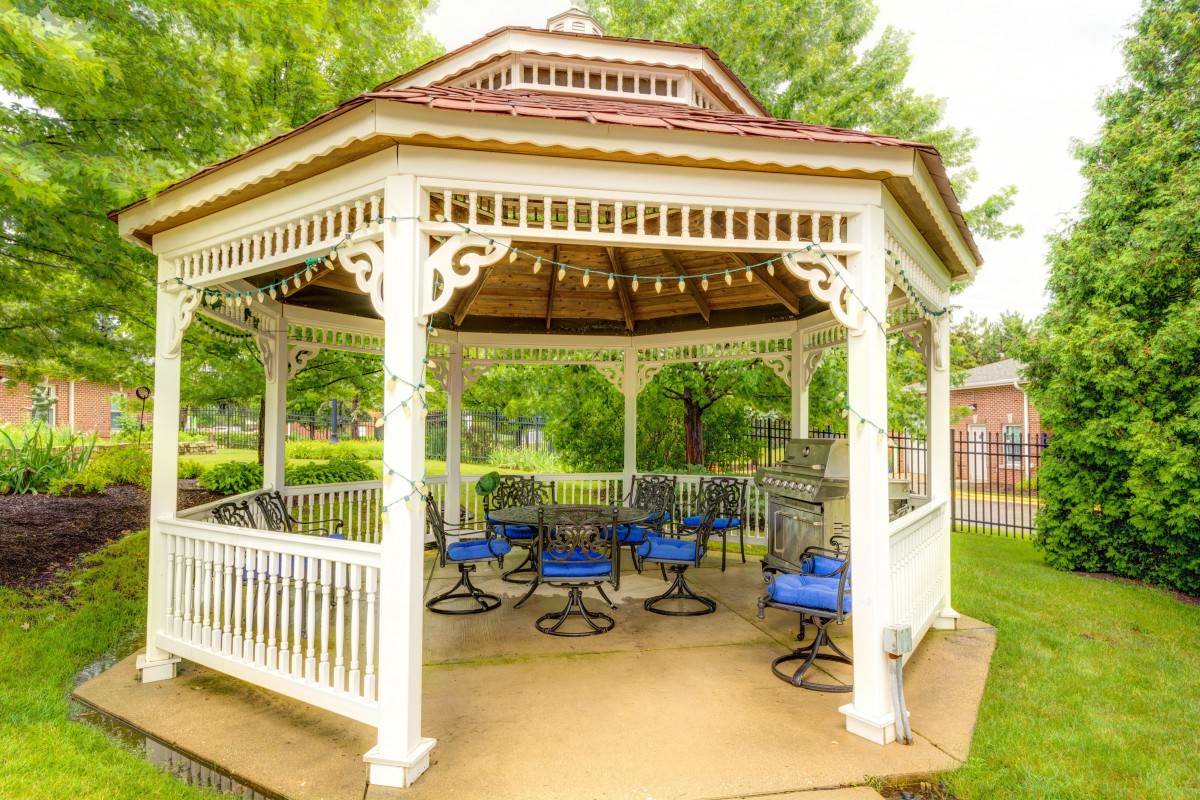 A charming gazebo with blue-cushioned chairs set in a lush garden.