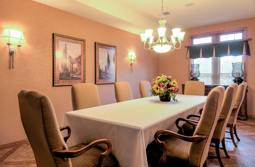 A traditional dining room with a large table, upholstered chairs, and a chandelier.