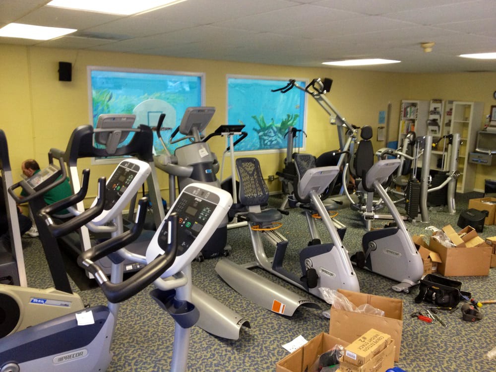 A gym room filled with various exercise machines including stationary bikes, treadmills, and ellipticals.