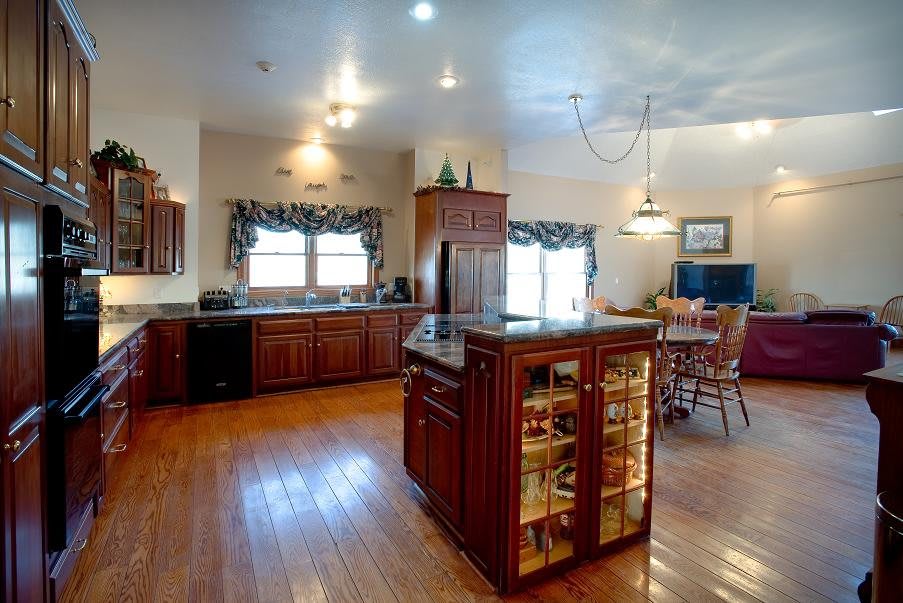 Spacious kitchen with a central island, wooden cabinets, and a dining area with hardwood flooring.