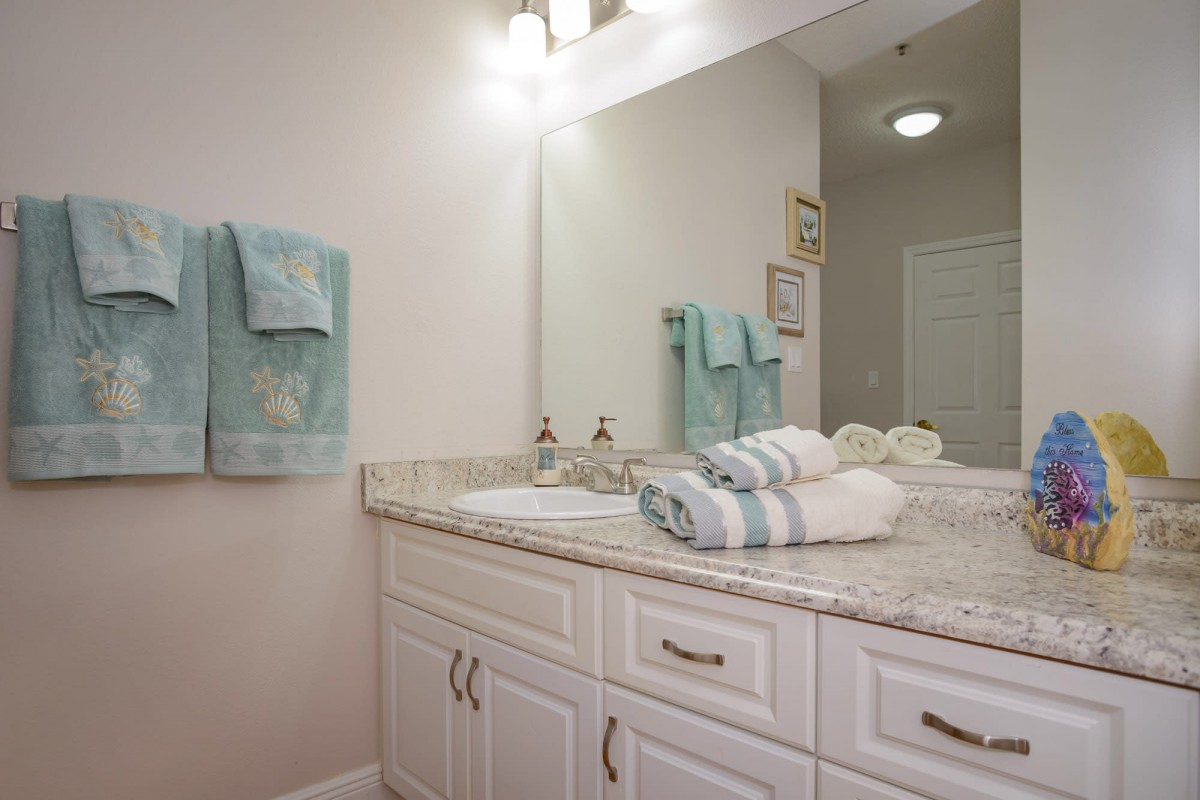 A neatly organized bathroom with a large mirror, soft lighting, and folded towels on the countertop.