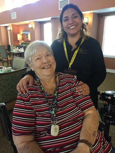 A joyful moment shared between a caregiver and a resident in an assisted living community.