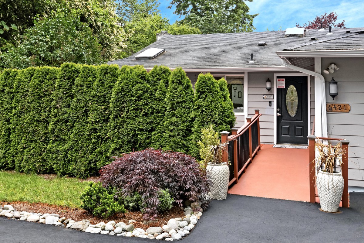 A cozy house with a well-maintained front yard featuring lush greenery and a paved driveway.