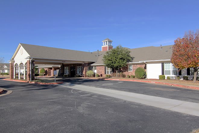 A modern brick building with a large parking lot under a clear blue sky.