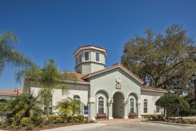 A residential building with a prominent entrance and well-maintained landscaping under a clear blue sky.