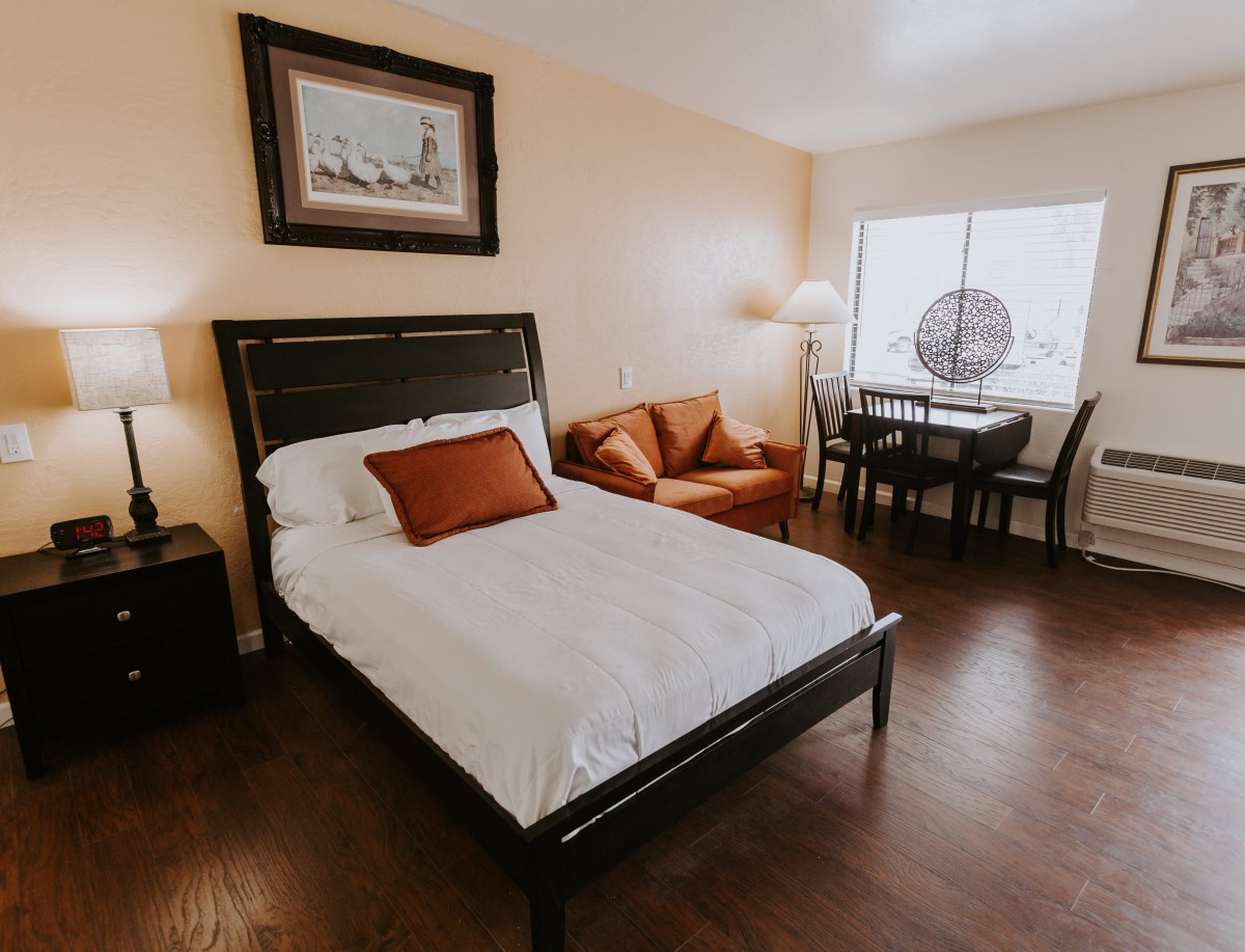 A cozy bedroom with a bed, sofa, and dining area.