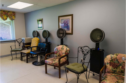 A cozy waiting area in a salon featuring various chairs and hairdryers.