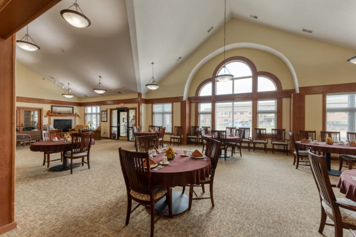 A spacious and elegantly furnished dining room with large arched windows.