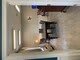 A modern open-concept living room and kitchen area featuring stylish furniture and tile flooring.