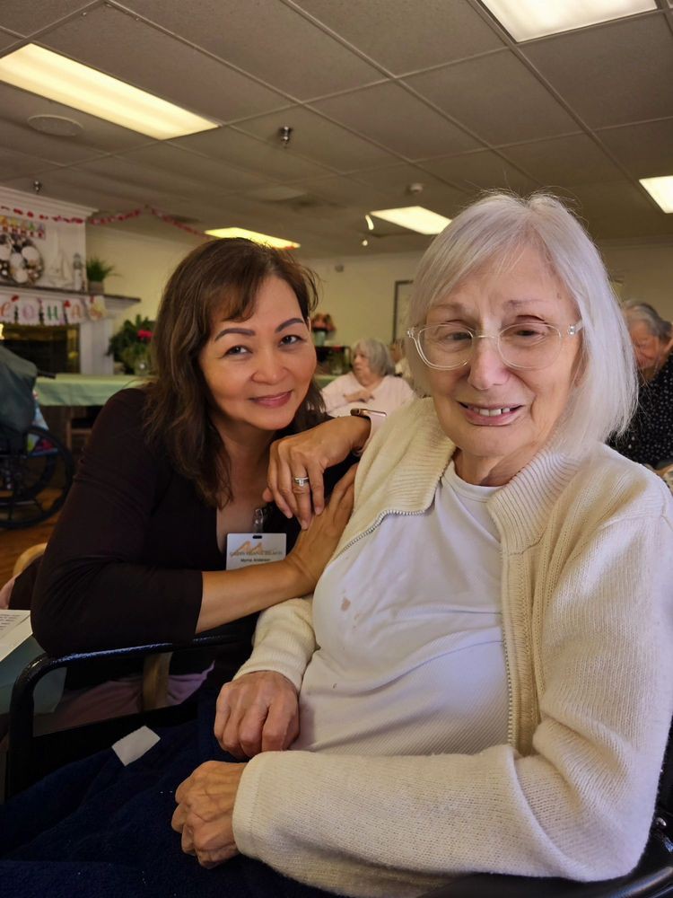 Two women smiling together indoors, showing a warm friendship.