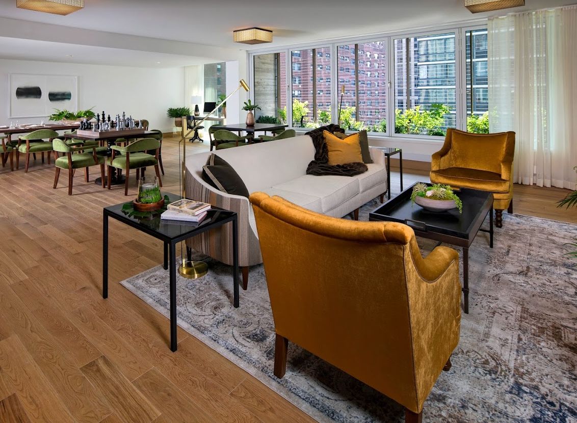 A modern living room with stylish furniture and large windows offering a city view.