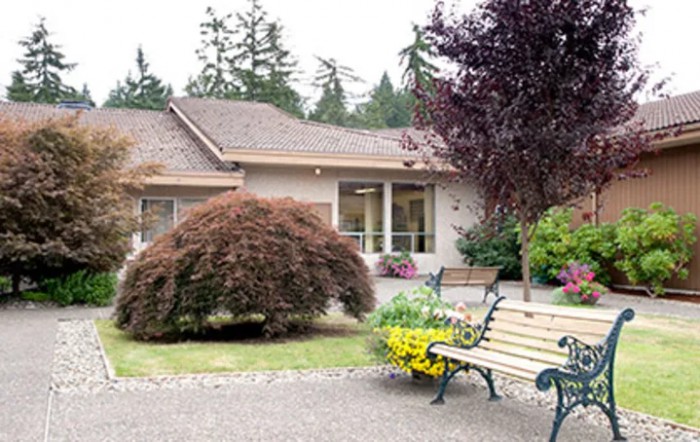 A cozy house with a landscaped garden and a bench in the foreground.