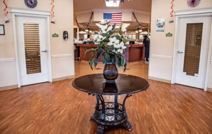 A decorated lobby area featuring a central table with flowers and an American flag in the background.
