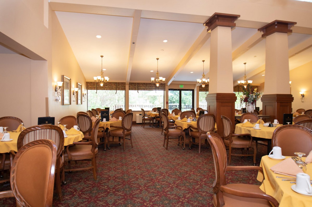 A spacious restaurant dining area with elegant wooden furniture and warm lighting.