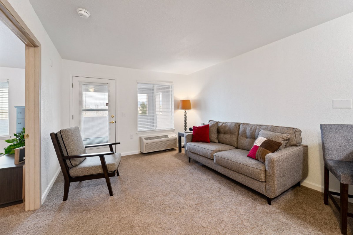 A cozy living room with a sofa, chair, and floor lamp.