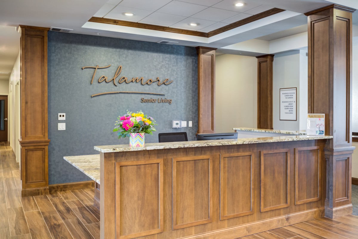 A modern reception area with a wooden desk and decorative flowers.