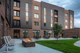 A modern apartment building with a courtyard featuring a fire pit and outdoor seating area.