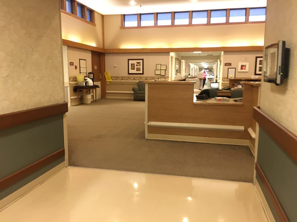 A spacious hospital hallway with seating areas and soft lighting.