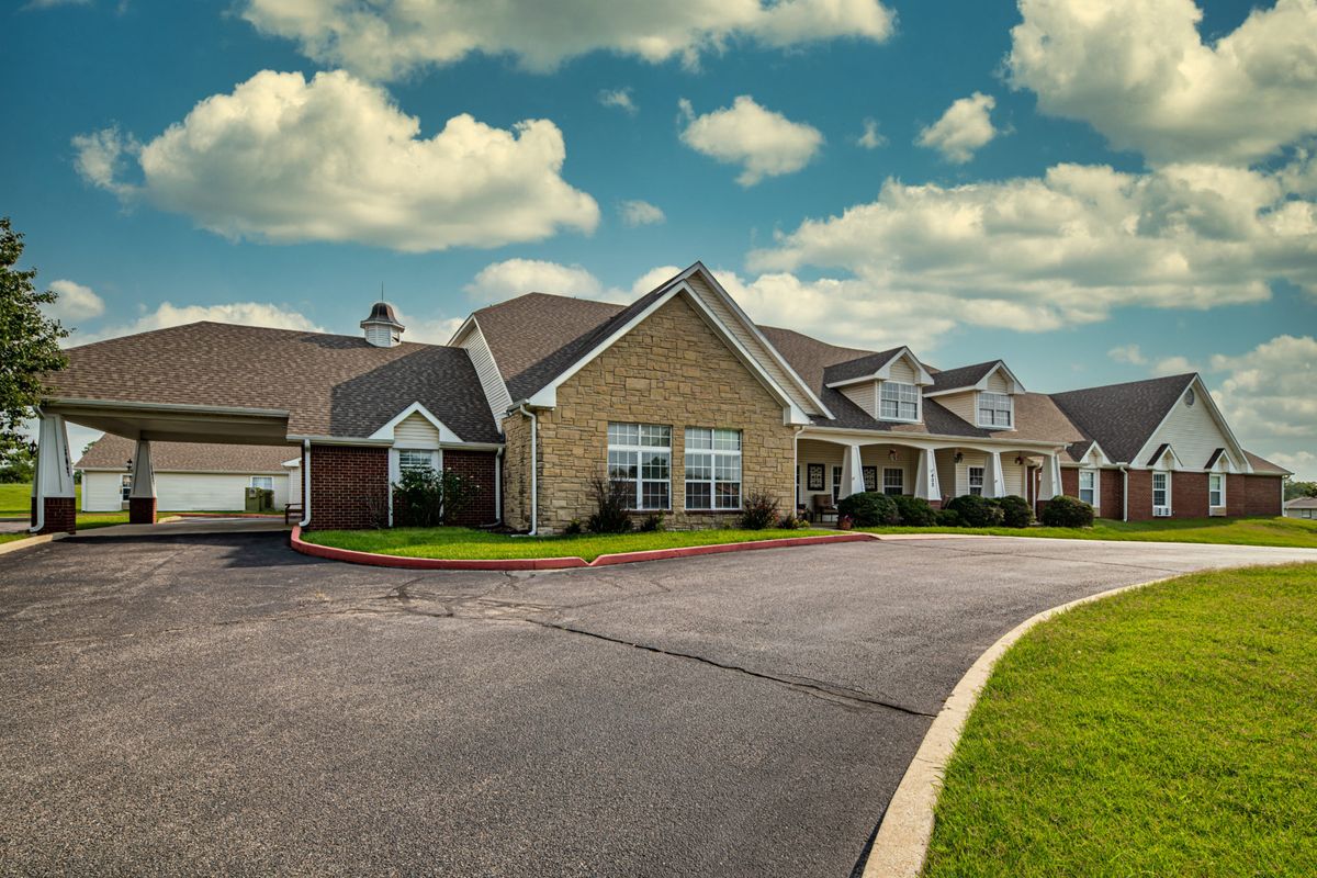 A suburban residential building under a partly cloudy sky.