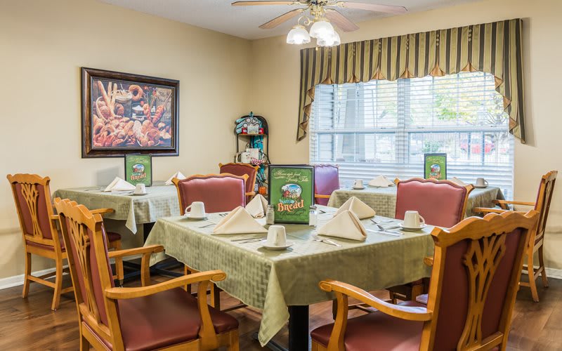 A cozy dining room with tables set for guests, featuring menus and neatly folded napkins.