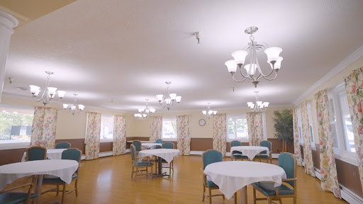 A bright and spacious dining area with tables and chairs, elegantly decorated with floral curtains and warm lighting.