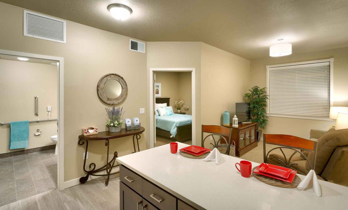 Modern dining area with a view into the bedroom, featuring clean decor and red accents.