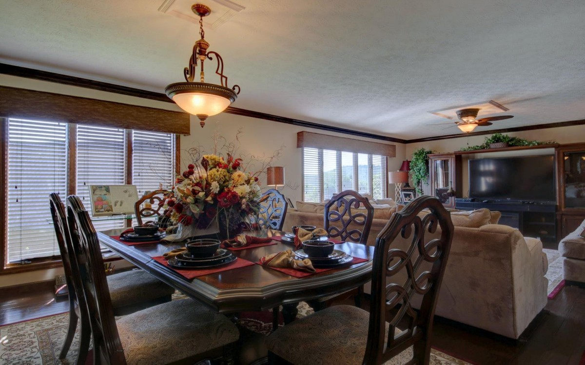 A cozy dining room with a decorated table and chandelier lighting.