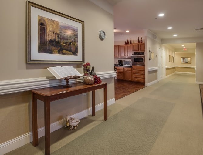 A cozy hallway with a wooden table displaying an open book and decorative items, leading to a kitchen area.