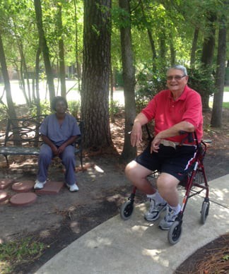 Two people enjoying a relaxing day in the park, with one seated on a walker and the other on a bench.