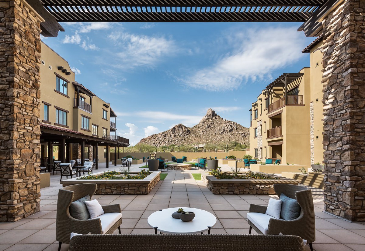 A luxurious resort with a stunning mountain view and comfortable outdoor seating area.