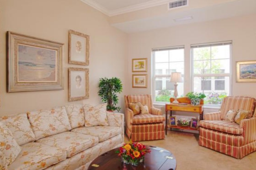 A cozy living room with a floral sofa, striped armchairs, and decorative artwork on the walls.