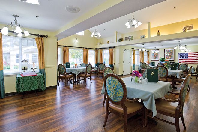 A well-lit dining area with elegant tables and chairs arranged on a wooden floor, complemented by large windows and tasteful decor.