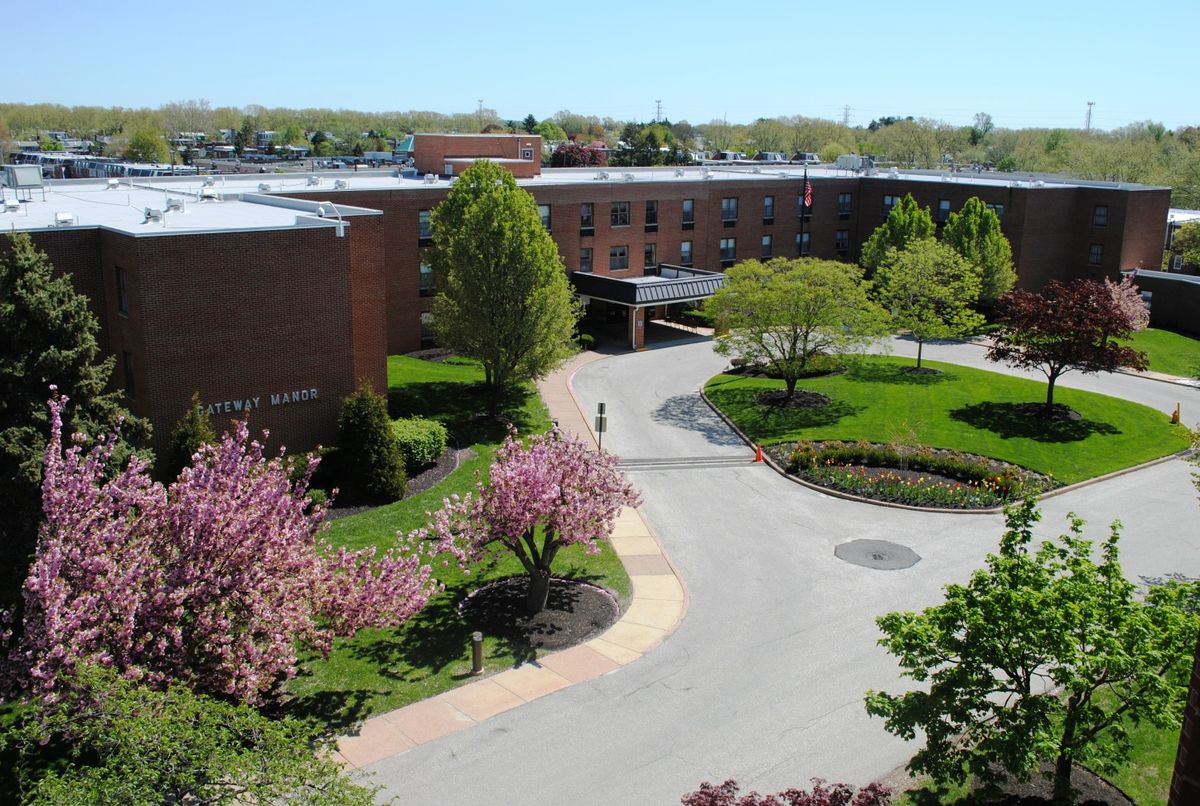 Aerial view of a campus with blossoming trees and a road winding through green lawns.