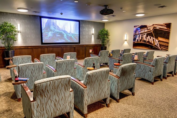 A cozy small-scale movie theater with comfortable seating and a projector screen.