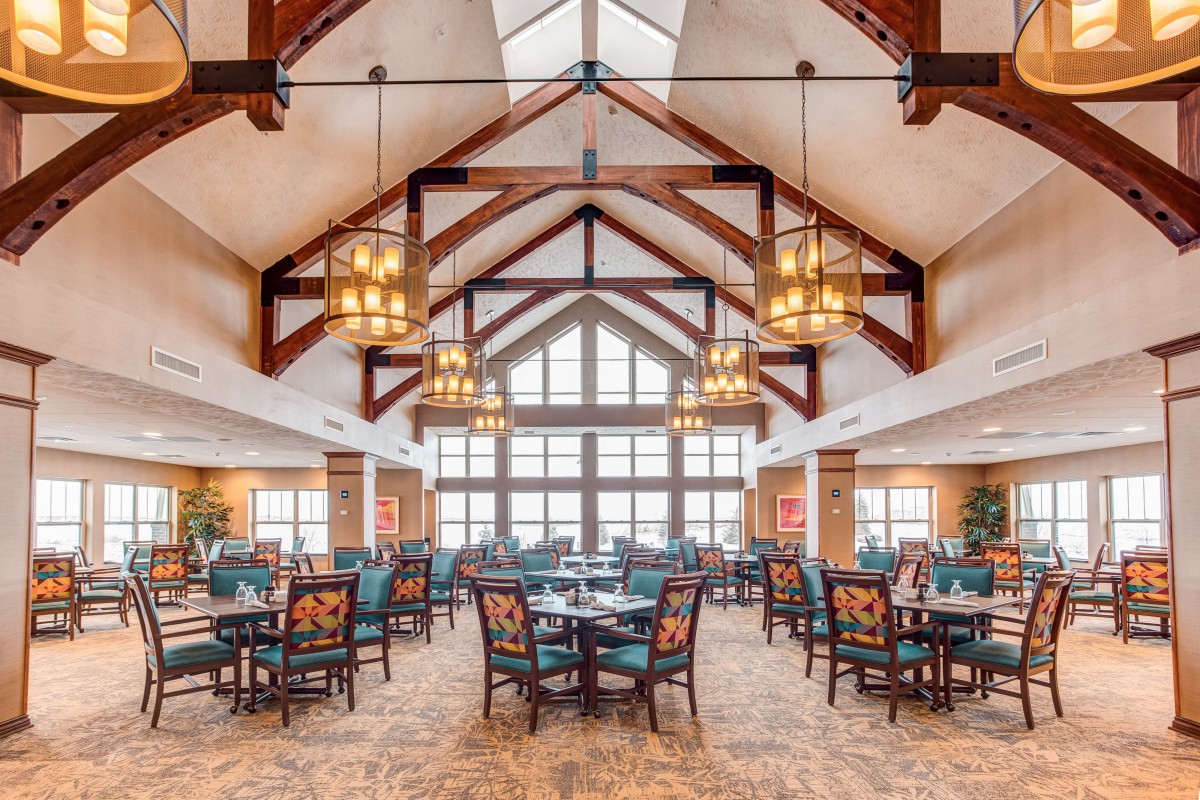 A spacious dining area with elegant chandeliers and wooden beam architecture.