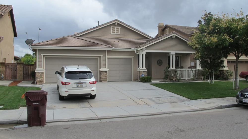A suburban house with a driveway and a car parked in front.