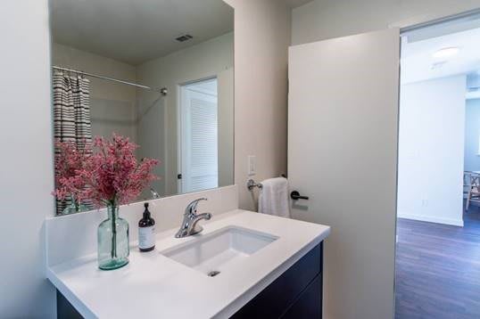 A modern, minimalist bathroom with a clean sink and decorative flowers.