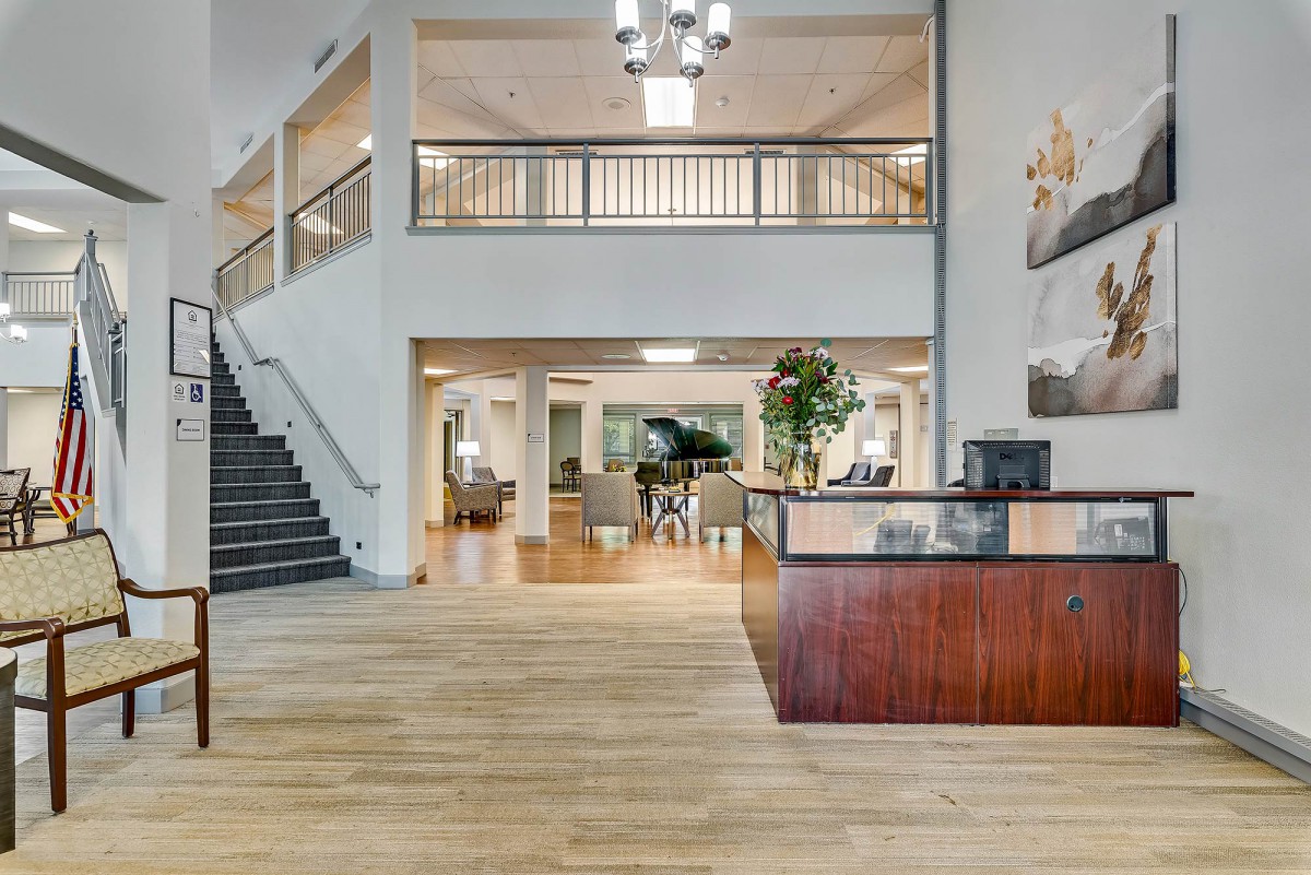 A spacious and elegant lobby with a reception desk, staircase, and grand piano.