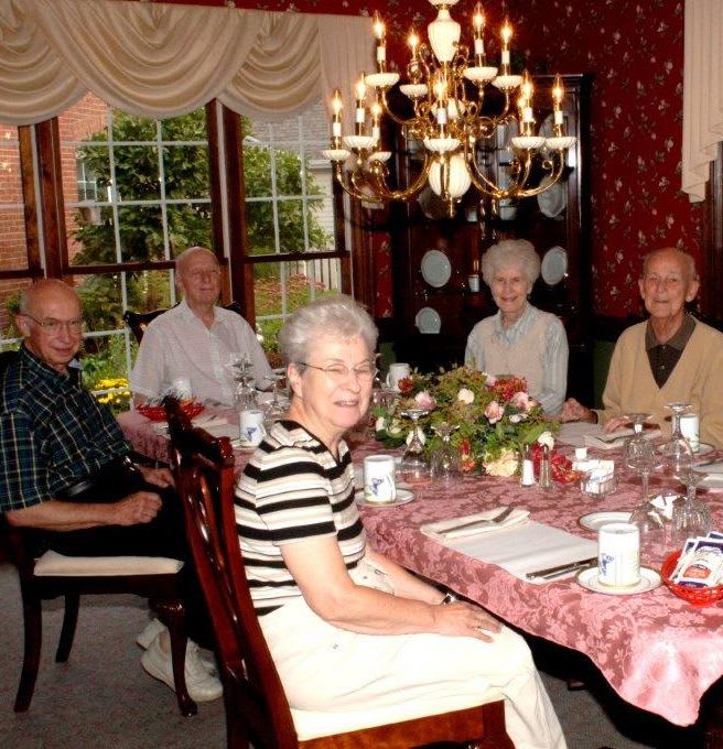 A group of seniors enjoying a meal together at a beautifully set dining table.
