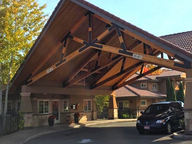 A building entrance with a wooden canopy and a parked car.