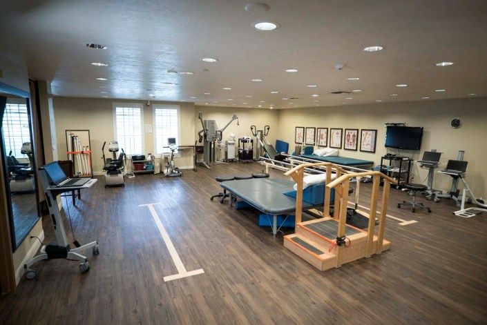 A spacious physical therapy and rehabilitation room equipped with various exercise machines and therapy equipment.