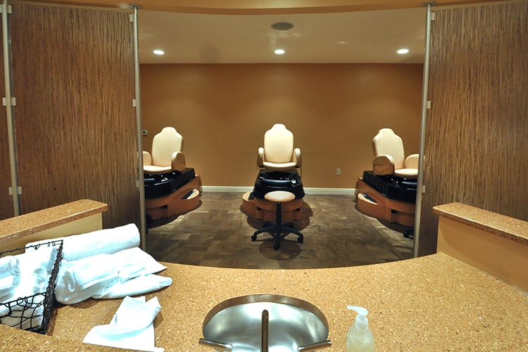 An empty spa room with three pedicure chairs arranged in a row.