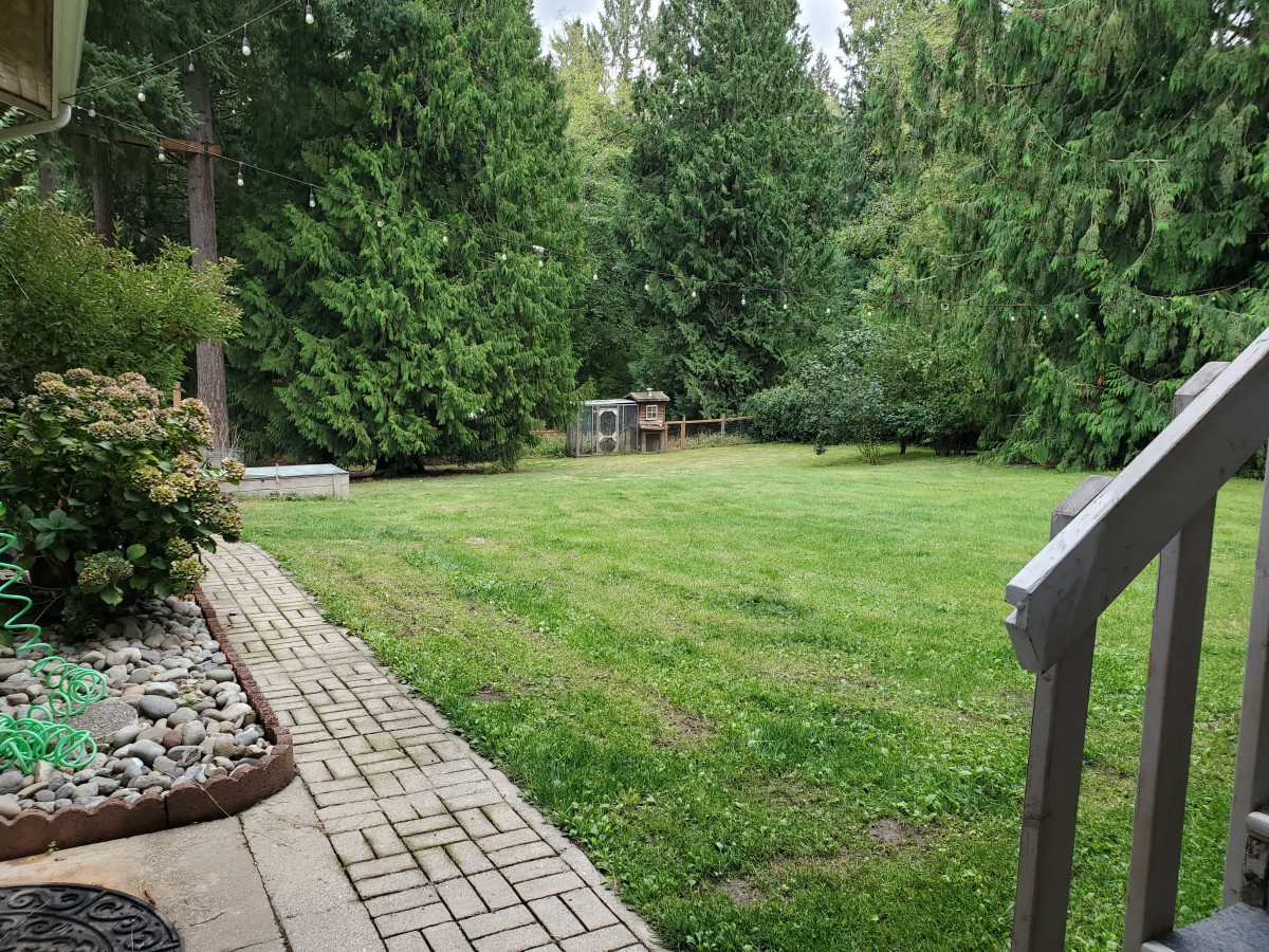 A lush green backyard with a manicured lawn and surrounding trees.