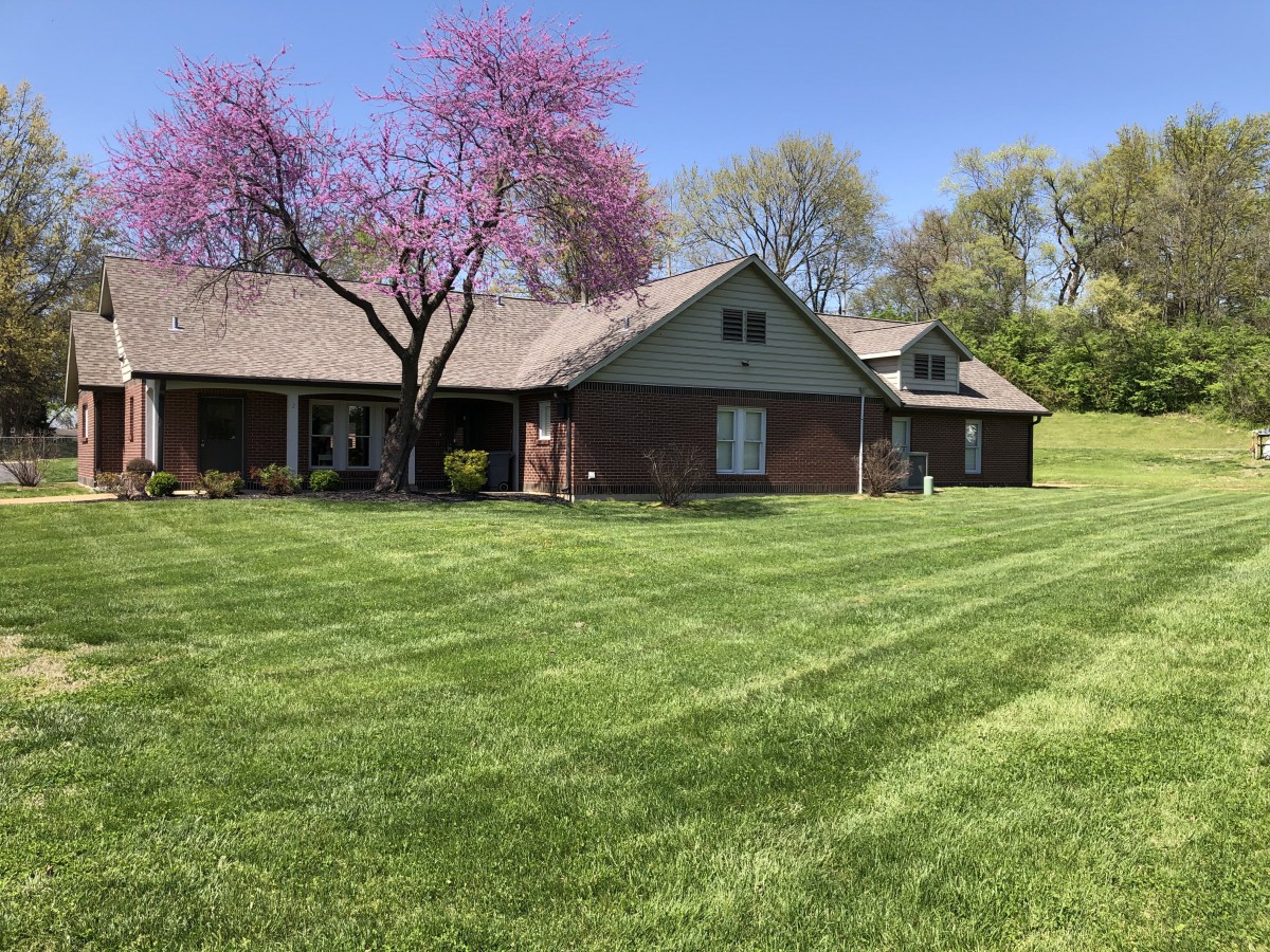 A suburban house with a well-maintained lawn and blooming trees during spring.