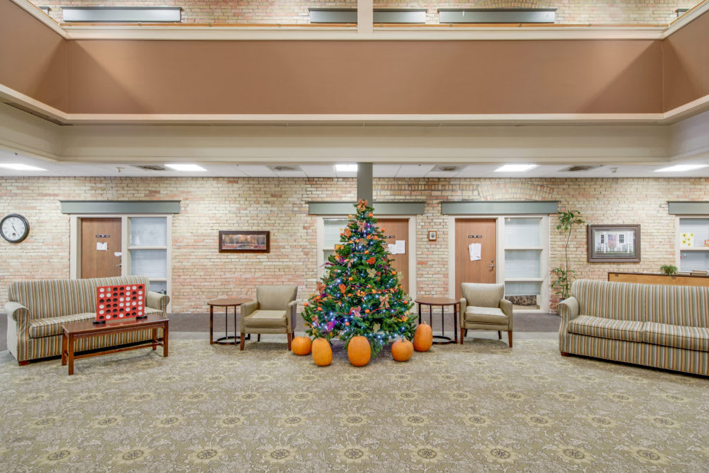 A lobby area featuring a decorated Christmas tree and pumpkins, surrounded by comfortable seating.