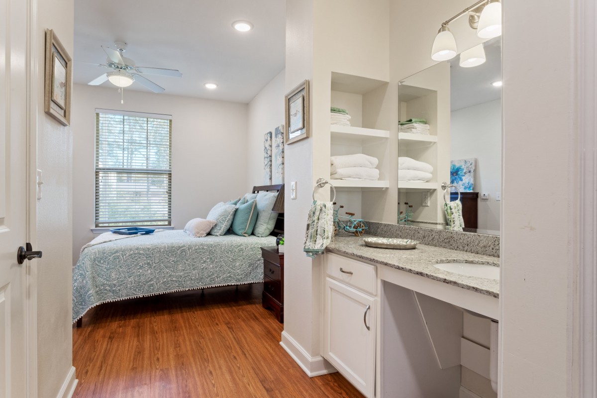 A modern bedroom with a comfortable bed and a well-organized vanity area.